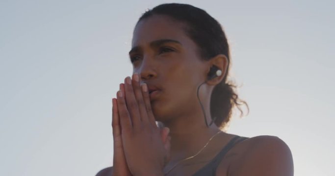 young hispanic woman runner preparing for intense running exercise female athlete training in urban city at sunrise wearing earphones listening to motivation music close up