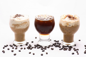 Cold coffee is spilled in clear glass on a white background in the studio.