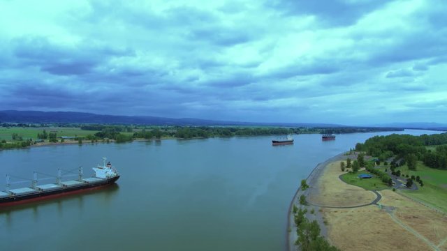 Drone aerial fly by of 1 cargo ship with 2 in the distance on the river waiting to load cargo