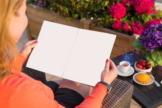Woman reading sample magazine, empty mockup for your own design.