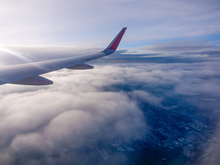 Obraz premium Wing of the plane Fly over the city in Thailand. In the blue sky and white clouds