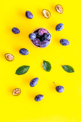 Blue plum for dessert. Purple plum and leaves pattern on yellow background top view copy space