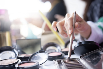 Top view of female table with makeup eye palette, foundation, brushes and others.