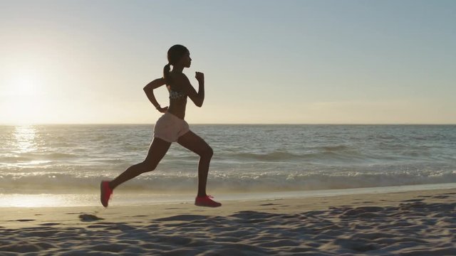 african american woman running training on beach jogging exercising fitness workout in beautiful seaside background at sunset