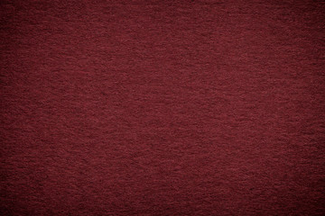 Texture of old dark red paper background, closeup. Structure of dense maroon cardboard