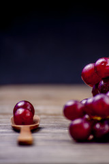 Grapes on a wooden spoon on a black background still life.