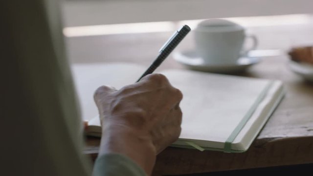 young woman hands writing to do list making notes in diary planning using journal reminder in coffee shop close up