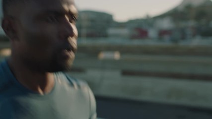 attractive young african american man running in city jogging athletic male exercising fitness workout in urban city at sunrise close up