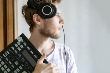 portrait of young bearded man sound producer  holding midi controller and headphones f