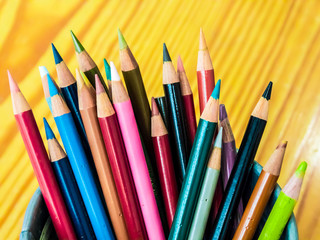 Fototapeta premium Multicolored pencils are combined in a steel box on a desk in the office.