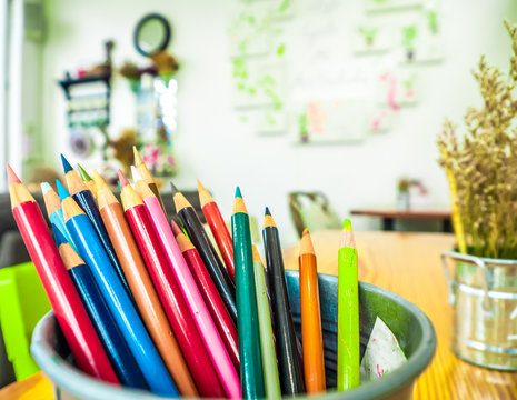 Multicolored pencils are combined in a steel box on a desk in the office.