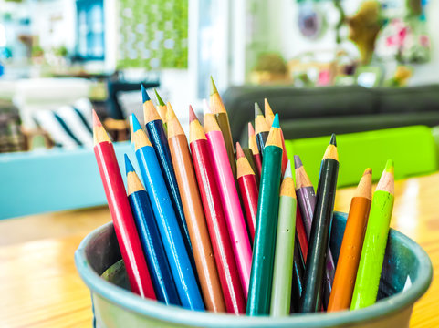 Multicolored pencils are combined in a steel box on a desk in the office.