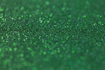 Green sparkling background from small sequins, closeup. Brilliant backdrop