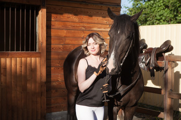 Young beautiful woman next to a horse in a stable