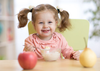 baby girl eating yogurt and fruits at home