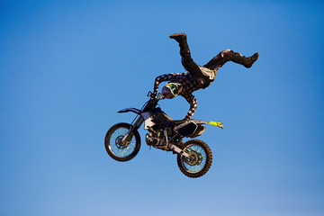 Fototapeta na wymiar Pro motocross rider riding fmx motorbike, jumping performing extreme stunt. Professional biker jumps
