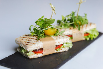 sandwiches of white bread, ham, tomato, cucumber, meat, olives, greens, lettuce, cheese on a plate
