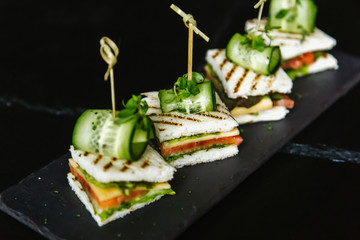 sandwiches of white bread, ham, tomato, cucumber, meat, olives, greens, lettuce, cheese on a plate