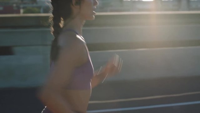 attractive caucasian woman athlete running on city street training intense cardio endurance workout focused female runner wearing earphones at sunrise