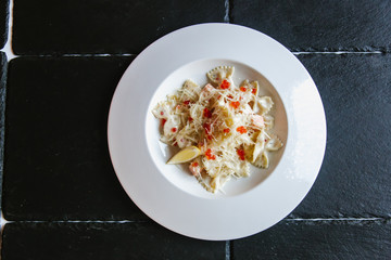 Pasta in a plate with seafood, red caviar, salmon on a dark background
