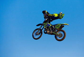 Naklejka na ściany i meble Pro motocross rider riding fmx motorbike, jumping performing extreme stunt. Professional biker jumps