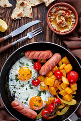 eggs, pumpkin, sausages in a skillet, vertical
