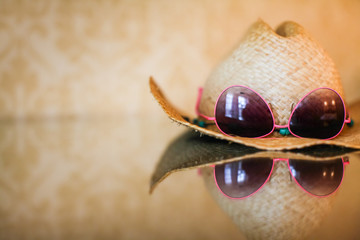 summer cowboy Woven hat and sunglasses with reflection on glass table