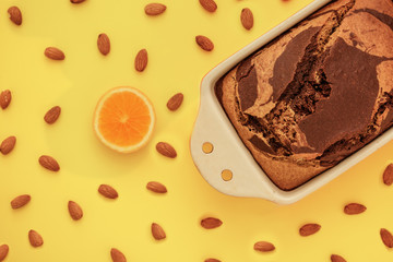 pound cake on a yellow background with almonds and orange, close-up, top view