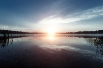 Fog over the lake, twilight over the lake, very dense fog, dawn, blue sky over the lake, the morning comes, the forest reflects in the water, surface water, clear morning sky, gothic, Grim picture