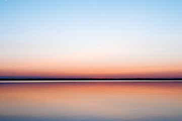 Beautiful, red dawn on the lake. The rays of the sun through the fog. The blue sky over the lake,...