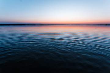Obraz premium ircles on the water against a beautiful, pink sunset. The magic time of day.