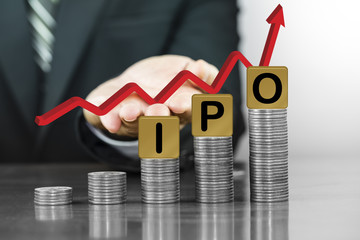 Businessman hand holding red arrow up with the letters IPO on money coin stack arranged as a graph, concept of Increased investment