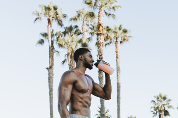 Muscular man drinking a protein shake - obrazy, fototapety, plakaty