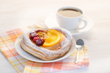 puff  cake  decorate with different fruit with cup of coffee on white table