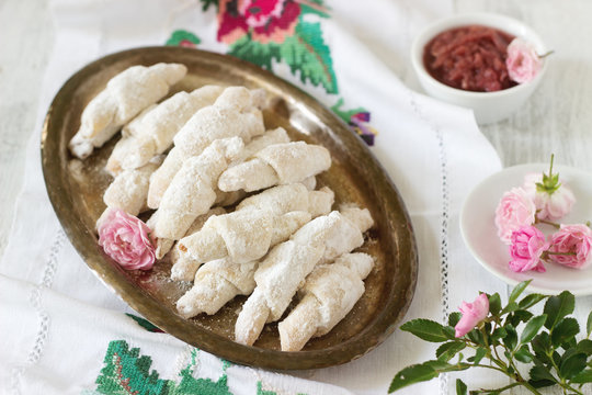 Traditional Romanian or Moldavian shortcake cookies with jam stuffing and a cup of tea on the light background.