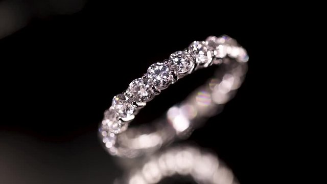 Engagement diamond ring rotating on black background, macro with shallow DoF