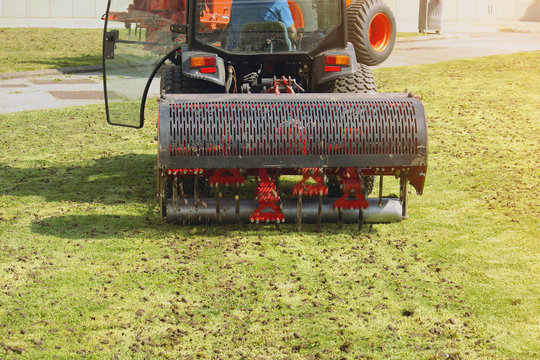 Gardener Operating Soil Aeration Machine On Grass Lawn