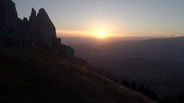 Aerial - Silhouette of 2 paragliders followed by a drone to film them at sunset