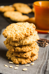 Stack of homemade oatmeal cookies on tissue with cup of tea or coffee
