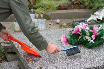 Cleaning grave on cemetery before All Saints' Day
