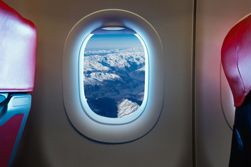 Sunrise ray light of Snow village on the alpine mountains as seen through window of an aircraft, plane interior touch screen ,vintage color selective focus