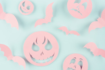 Halloween background - pink spooky faces emoji and bats of cut paper on pastel trendy mint blue color, pattern.