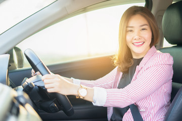 Happy confident and beautiful women,young asian businesswoman in casual wear,she smiling while driving a car against sunset rays Light shine sky Concept
