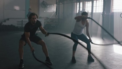 fitness athletes training intense workout using battle ropes team exercise challenge in gym friends enjoying healthy bodybuilding lifestyle together slow motion