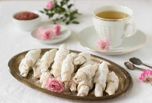 Traditional Romanian or Moldavian shortcake cookies with jam stuffing and a cup of tea on the light background.