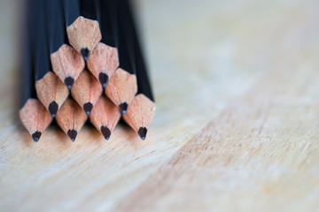 Wooden black pencil pyramid form on old wood table, image for background, wallpaper, copy space