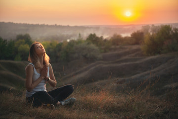 A girl prays in nature