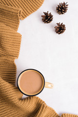 Knitted shawl, cup of coffee and cones on white background