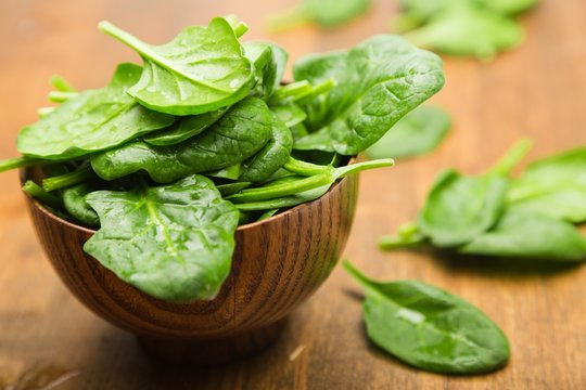 Young Spinach Leaves On Wooden Table And More In Bowl Close-up