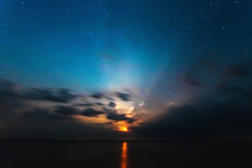 A lighting bolt striking from bright clouds in the night. Belarus. The starry sky.